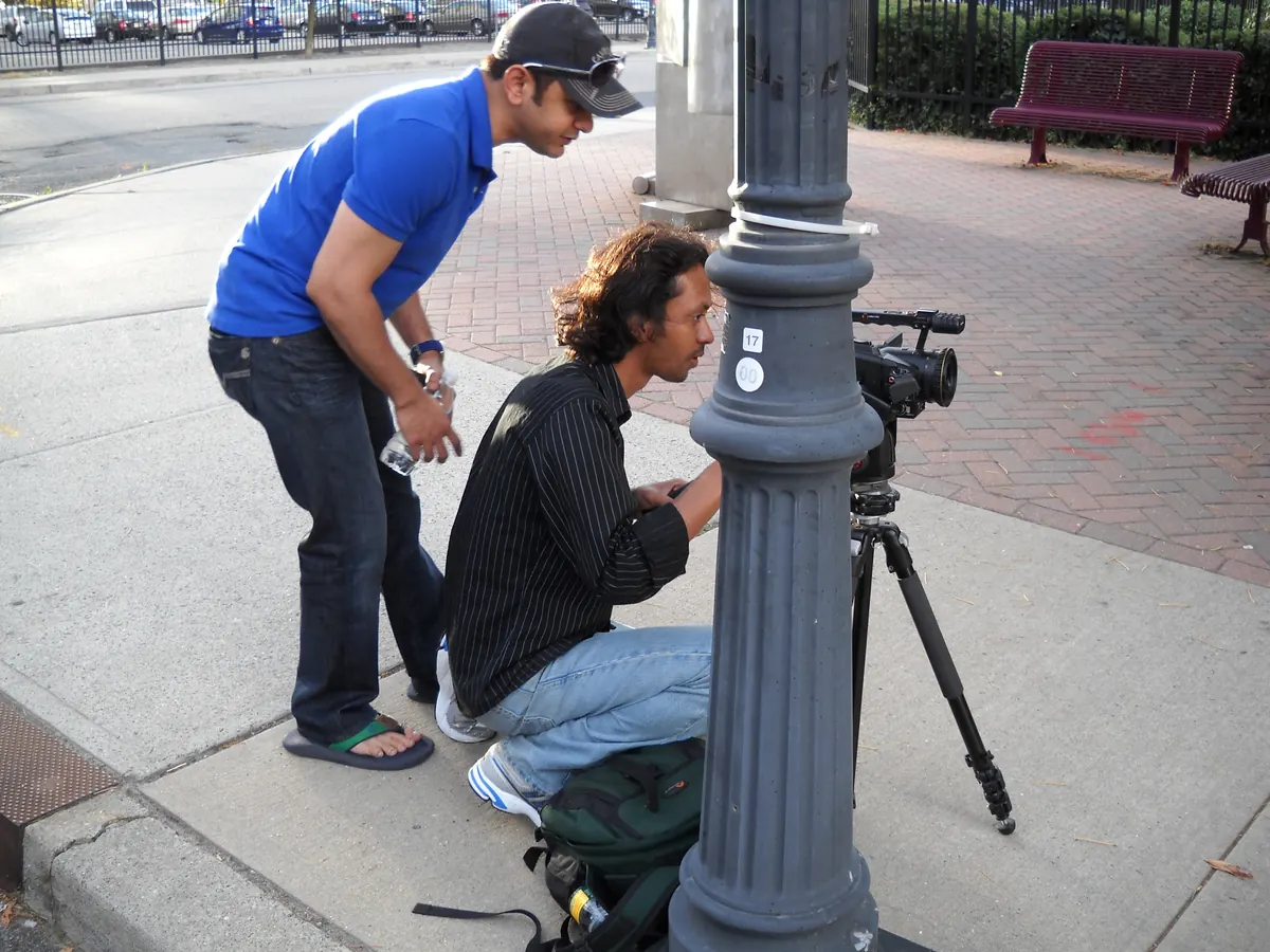 Crouched at the tripod on the sidewalk